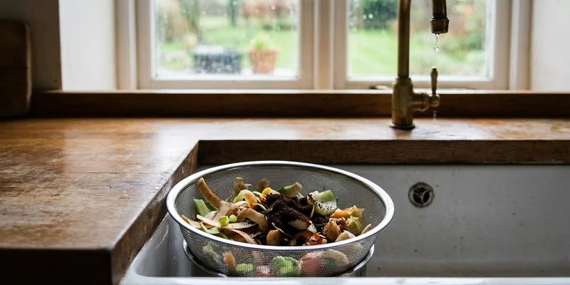 Close-up of a stainless steel mesh sink strainer catching food debris in a kitchen sink drain